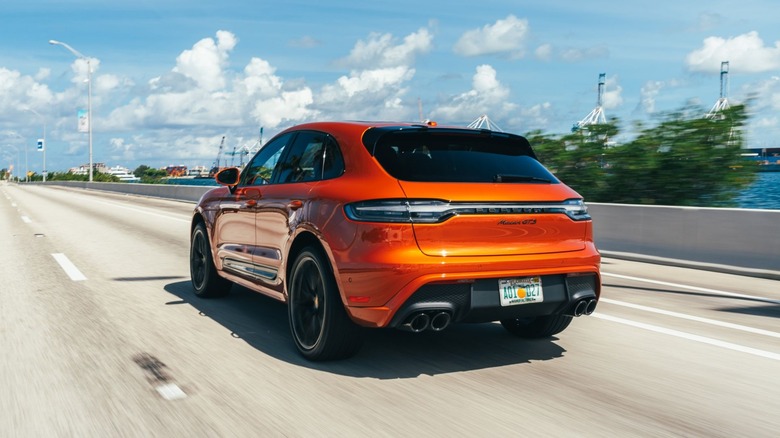 An orange Porsche Macan GTS on a highway.