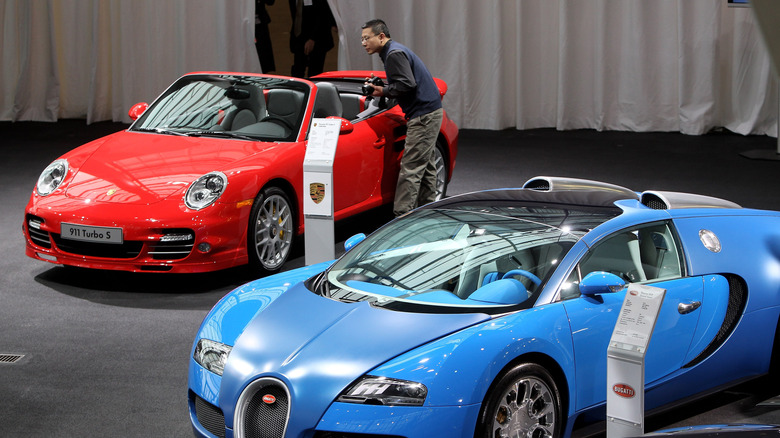 Journalists look at Porsche and Bugatti cars, both brands of which belong to Volkswagen, at VW's annual press conference on March 11, 2010 in Wolfsburg, Germany.