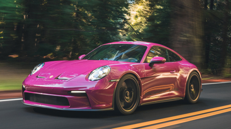 front three-quarters shot of a Ruby Star Neo 911 S/T driving on a two-lane forest road past blurred trees