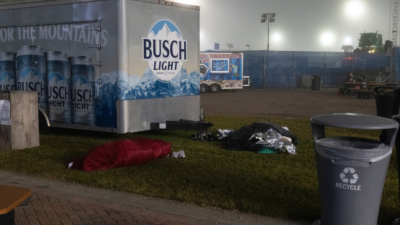 Two fans sleeping on a glass patch next to a beer trailer in the Daytona fan zone