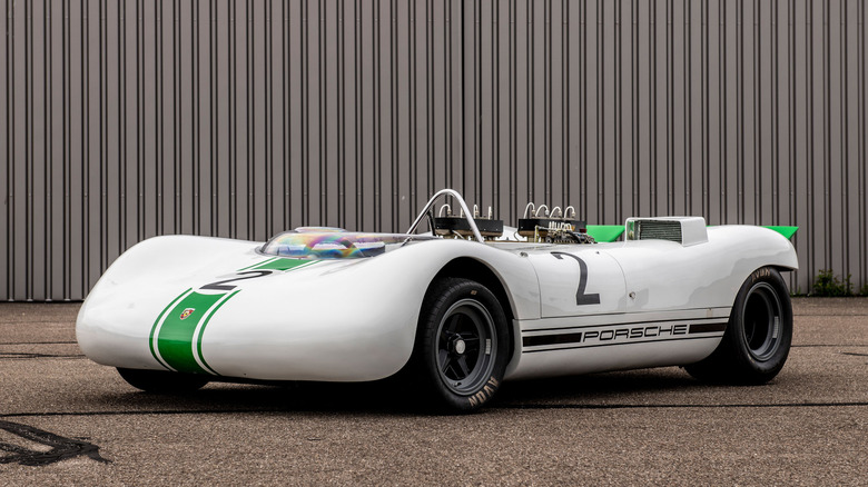 A white Porsche 909 Bergspyder race car with a green stripe, parked