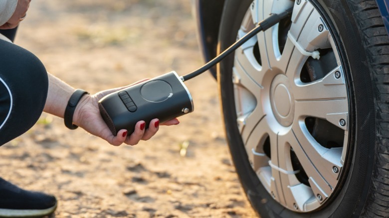 A person using a cordless portable tire inflator