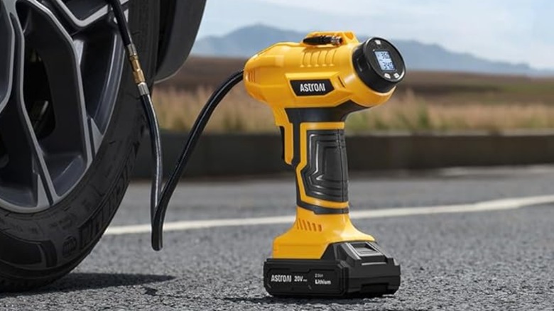 A yellow AstroAI portable tire inflator filling a car's tire