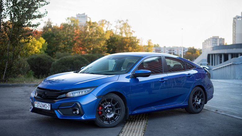 A blue Honda Civic Si sedan sitting on aftermarket Sparco wheels.
