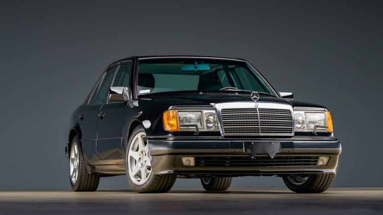 A black Mercedes-Benz 500E looking tough in black paint, showing its widened fenders and thick wheels.