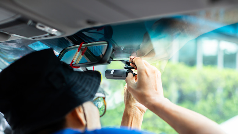 A person installing an aftermarket dashcam in their car