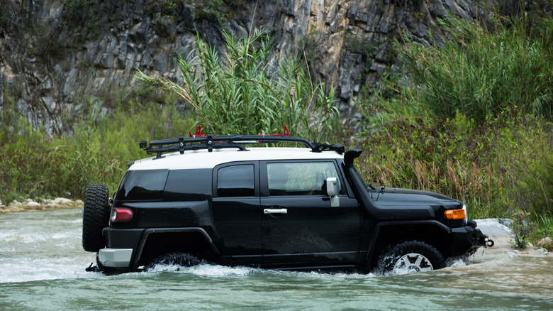 Black FJ Cruiser fording a river.