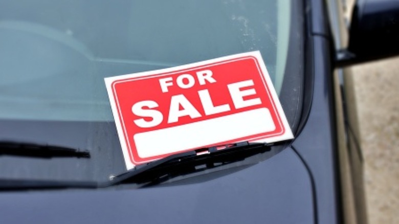 A red for sale sign on the windshield of a dark car