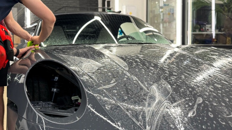 Paint protection film being applied to the nose of a gray Porsche 911