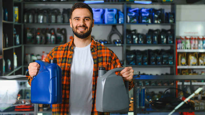 Customer holding two bottles of engine oil in an auto parts store