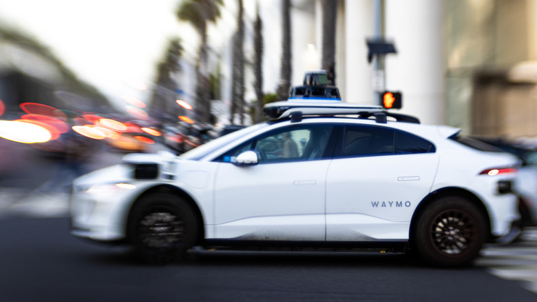 A Waymo taxi driving through an intersection
