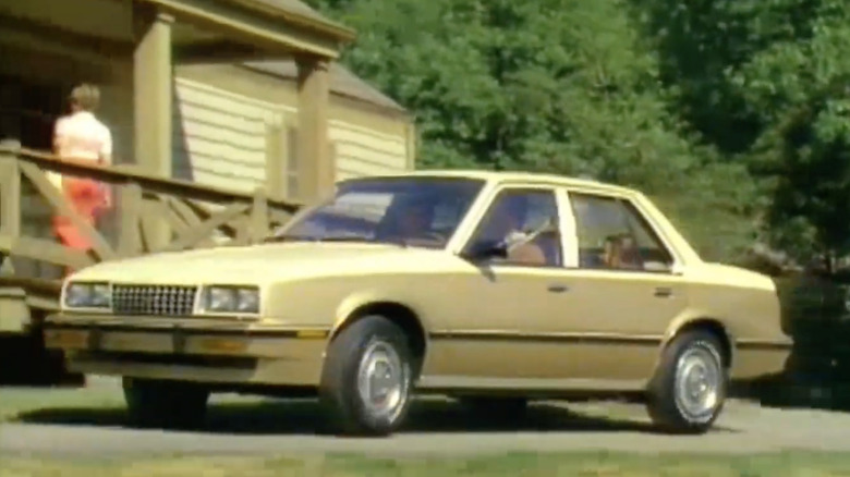 A Chevrolet Cavalier sits parked near a house.