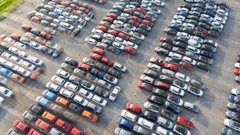 A lot full of cars is shot from above.