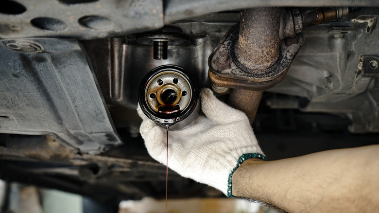 a person removing a used spin-on oil filter