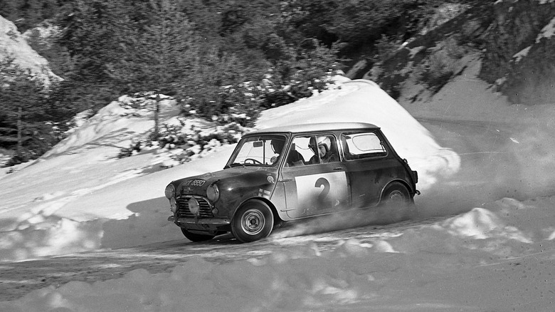 A black and white image of a Mini Cooper S taking a tight curve in the snow at the 1966 Monte Carlo Rally.