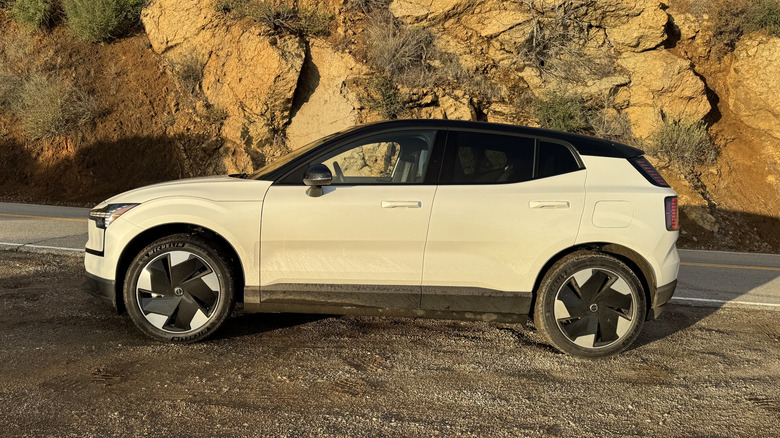 Side view of a white EX30 at golden hour in front of giant boulders with shrubs