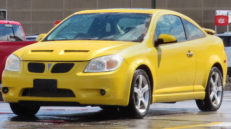 Competition Yellow 2007 Pontiac G5 GT Coupe in a parking lot with other cars and a building in the background