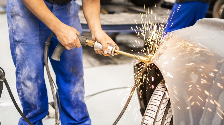 Auto body mechanic fixing fender