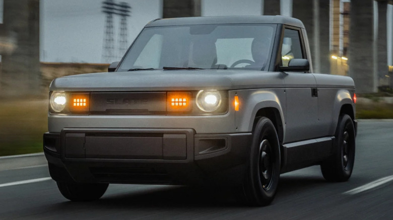 A silver 2026 Slate pickup driving with lights on
