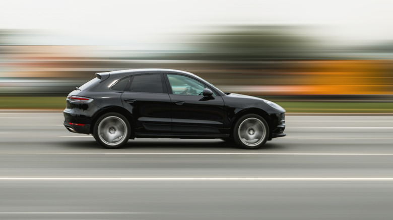 Side view of a black crossover SUV speeding down a highway
