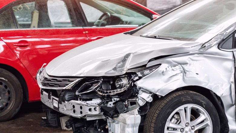 A wrecked silver car next to a red car