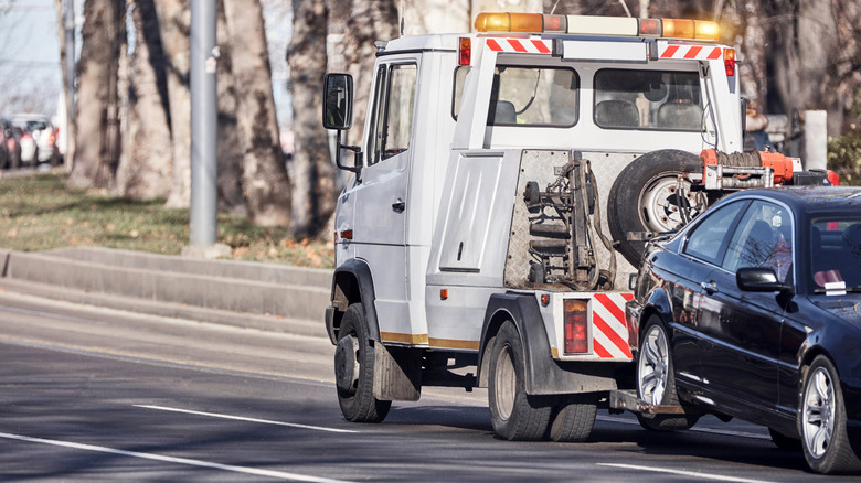 Tow truck carrying improperly parked car or repossessed vehicle.