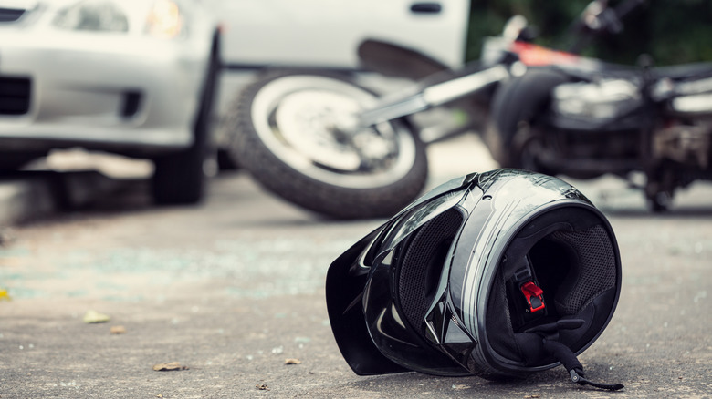 Stock photo showing a motorcycle helmet on the ground following a crash with a car