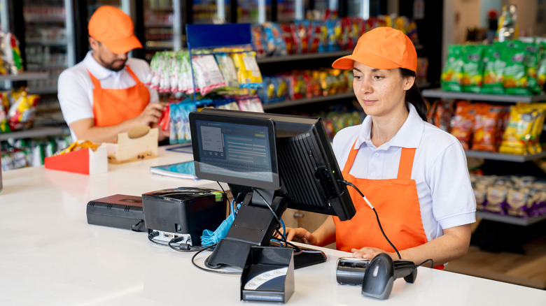Two gas station clerks working near a register
