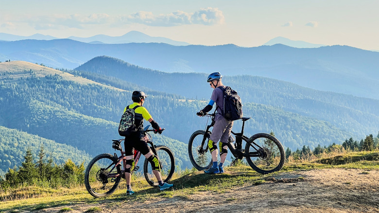 Two cyclists riding electric bikes outdoors.