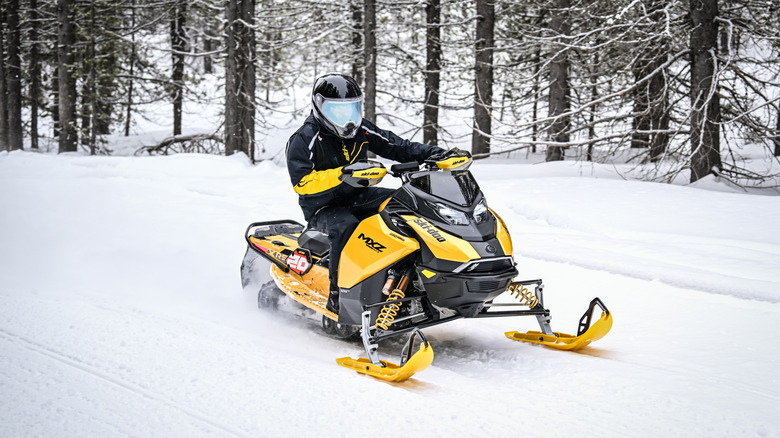 A rider on a yellow Ski-Doo MXZ on a snowy trail