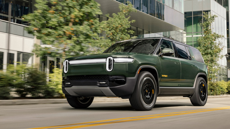 Front 3/4 view of a green Rivian R1S in motion.