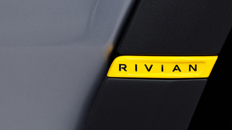 Yellow Rivian badge on the side of a black car