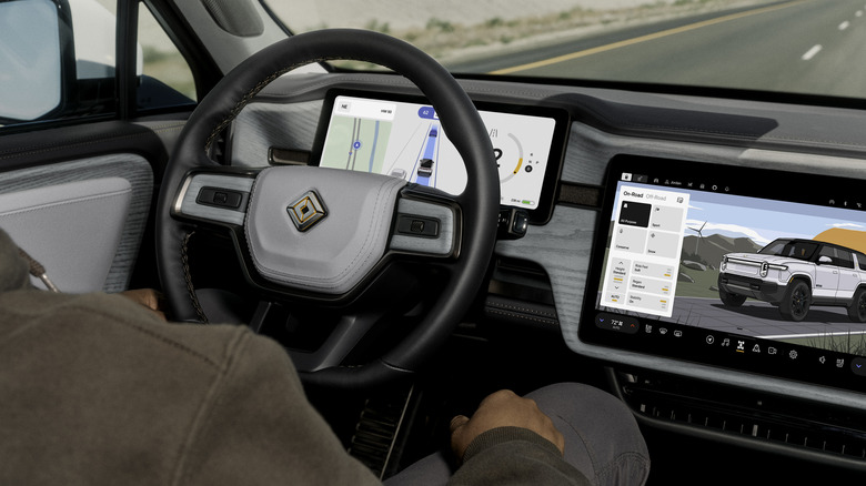 An interior shot showing the Rivian R1S's dashboard with trees out the windshield