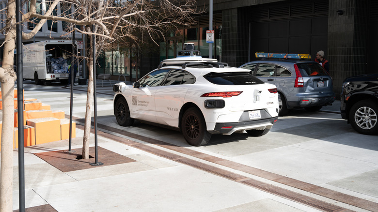 Rear 3/4 view of a Waymo robotaxi driving through the Mission Hill area of San Francisco
