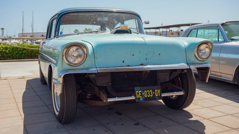 A blue classic car with without a bumper