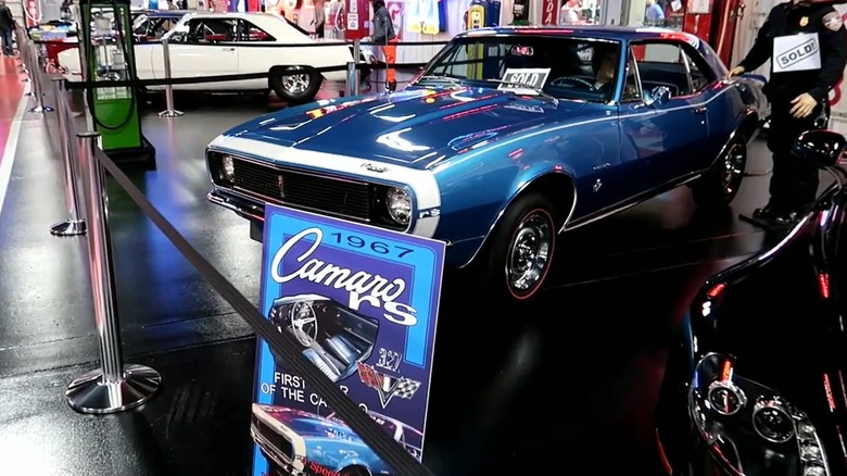 A Dream Car Museum exhibit prominently featuring a blue 1967 Chevrolet Camaro RS coupe with other cars and mannequins nearby