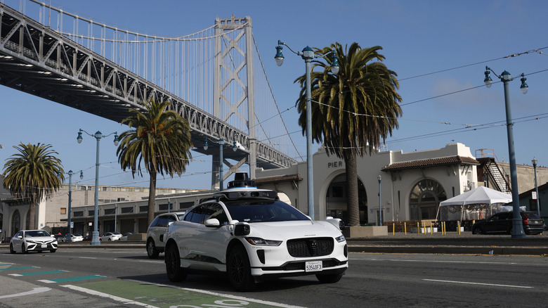 SAN FRANCISCO, CALIFORNIA - DECEMBER 08: A Waymo robotaxi drives along The Embarcadero on December 08, 2025 in San Francisco, California. Self-driving taxi company Waymo said it is voluntarily recalling software in its autonomous vehicles after Texas officials documented at least 19 incidents this school year in which the cars illegally passed stopped school buses, including while students were getting on or off.