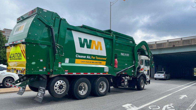 A waste management trash truck driving down the freeway