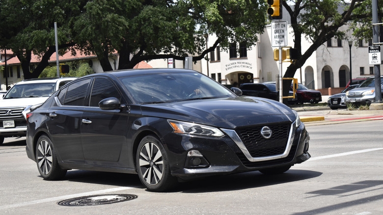 a black nissan altima lurking through traffic on a sunny day