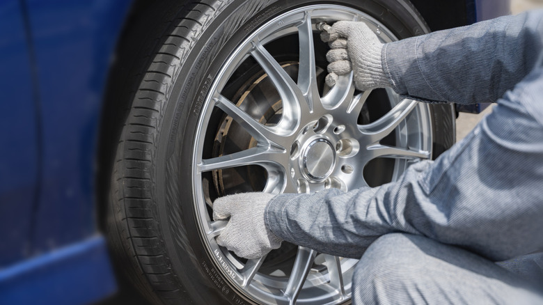 A technician mounting a wheel and tire combo into the hub