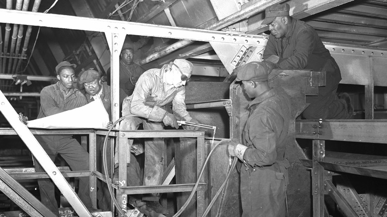 A vintage photo of Ford factory workers wearing Carhartt jumpsuits.