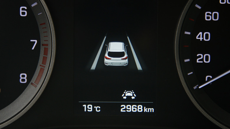 A vehicle's lane-keep assistance display surrounded by vehicle gauges for RPM and speed.