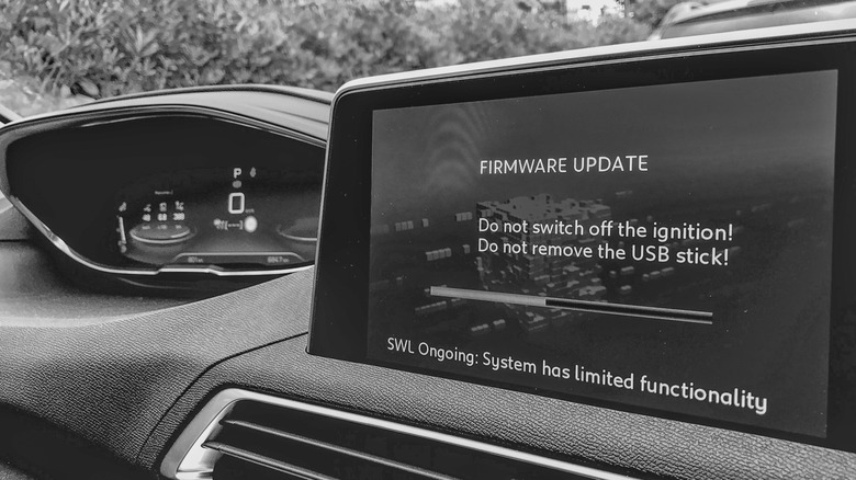 A black and white image of a vehicle's screen installing a firmware update.