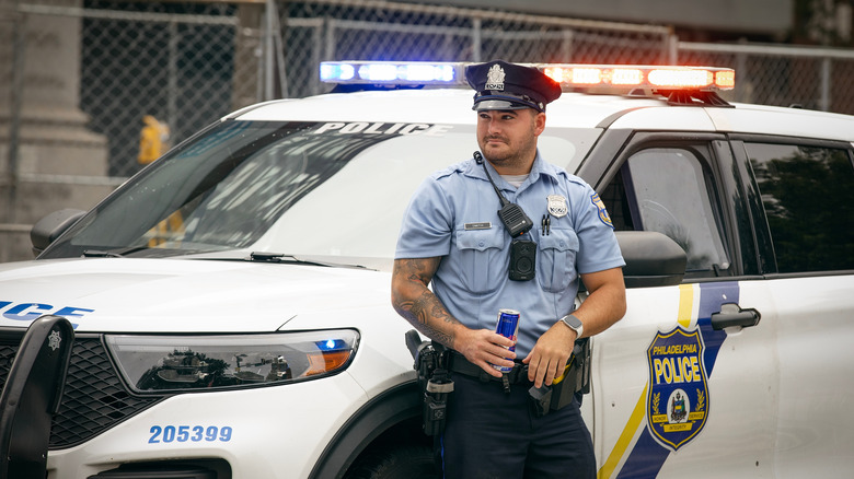 A Philadelphia police officer stands in front of his cruiser
