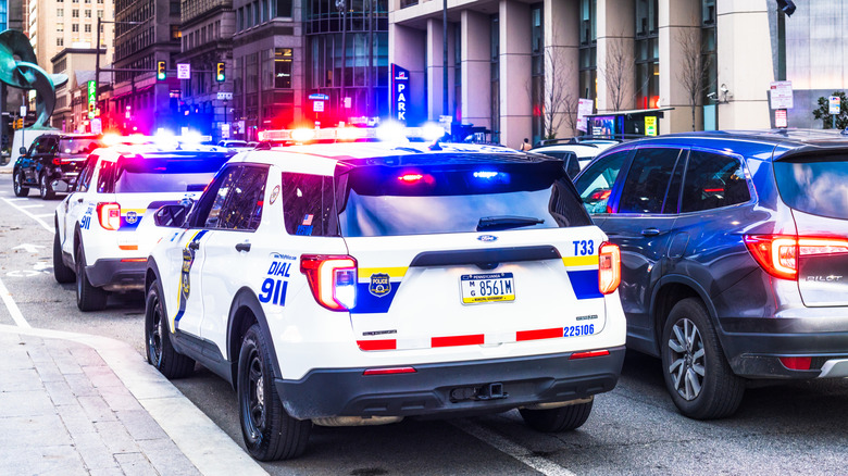 Philadelphia police cruisers flash their lights on the street