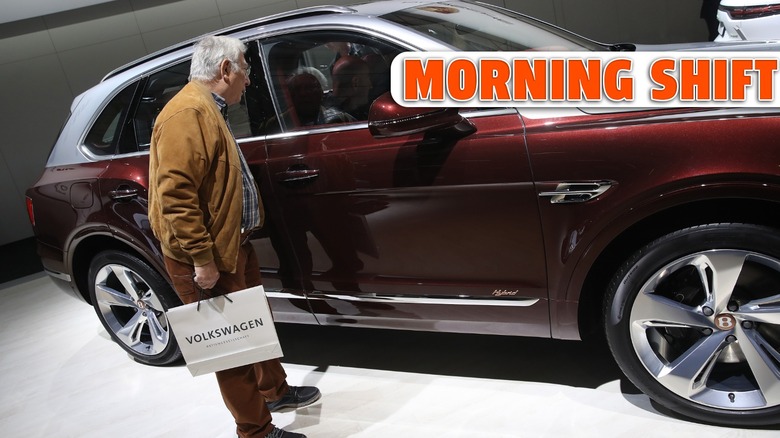 an elderly man looks into a VW SUV on the floor of the Berlin Auto Show