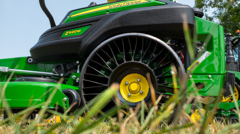 A green John Deere zero-turn lawnmower fitted with an airless tire