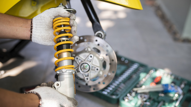 An auto mechanic holds a shock absorber during a repair