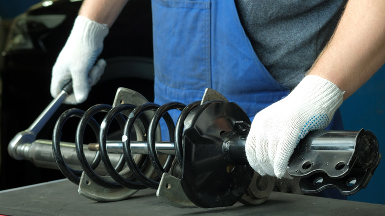 Auto mechanic holds a strut apparatus on a table