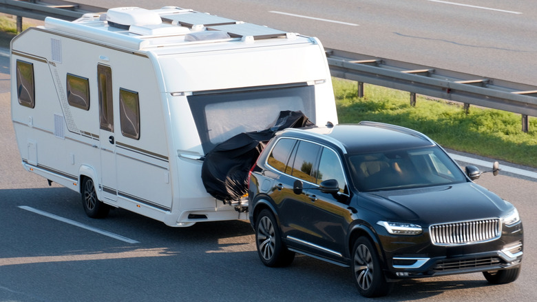 A black SUV towing a white camping trailer